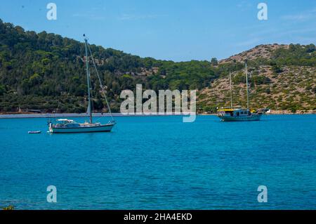 Two white boats sailing close to the coast blue aegean sea in Greece Stock Photo