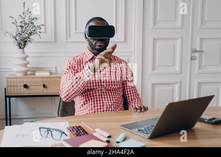 Young African ethnicity man entrepreneur in VR headset glasses immersed in 3D gaming Stock Photo