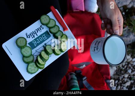 woman on an evening hike makes snack,cup,breadboard,snack,break,rest,cucumber,europe,germany,bavaria,upper bavaria,werdenfels,mittenwald Stock Photo