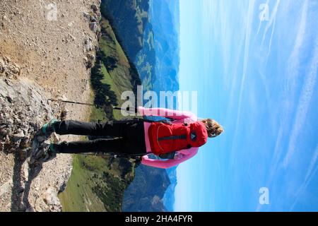 young woman from behind with backpack on hike to geigelstein (1808m),nature reserve,aschau im chiemgau,upper bavaria,bavaria,germany