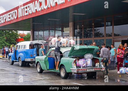 Cubans loading their old American cars with loads of imported foreign merchandise in front of the Antonio Maceo Airport in the city Santiago de Cuba Stock Photo