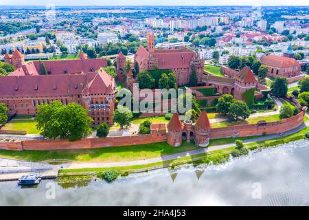 Medieval Malbork (Marienburg) Castle in Poland, main fortress of the Teutonic Knights at the Nogat river. Aerial view in fall in sunset light. Stock Photo