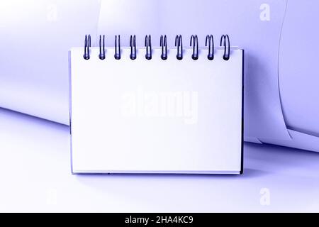 White empty office copybook with spiral mock up for notes and messages on trendy Very Peri color background. Blank open notepad page template with cop Stock Photo