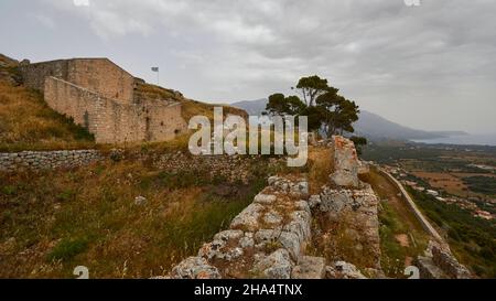 greece,greek islands,ionian islands,kefalonia,agios georgios castle complex,byzantine,16th century,capital kefalonia until 1757,cloudy weather,gloomy mood,view over fortress walls in direction southwest,trees on fortress wall,the greek national flag wafts over the top left ruins Stock Photo