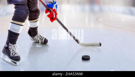 Low angle view of ice hockey player with stick on ice rink controlling puck and copy space. Stock Photo