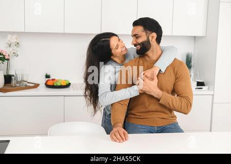 Close-up portrait of happy multi-ethnic couple in love hugging and looking at each other with cheerful smiles. Relationships concept. Stock photo Stock Photo