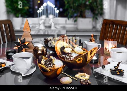 Advent season. In the dining room the table is set with bronze and black decorative elements. Homemade baked cookies and coffee. Stock Photo