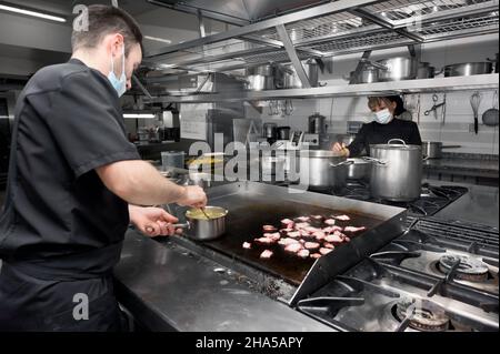 group of chefs cooking together in the kitchen at restaurant wearing protective medical mask in coronavirus new normal concept. High quality photo Stock Photo