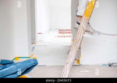 construction site,redevelopment and renovation of an apartment,painter stands on a ladder in an empty room Stock Photo
