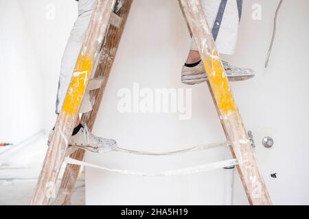 construction site,redevelopment and renovation of an apartment,painter stands on a ladder in an empty room Stock Photo