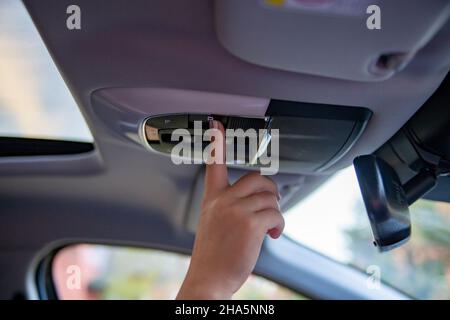 hand push button on ceiling console and open panoramic roof window in modern car Stock Photo