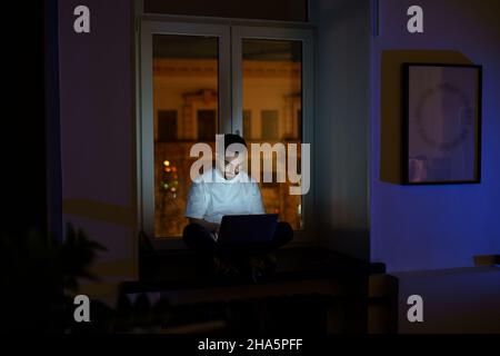 Freelancer programmer work on laptop late at night. Web developer coding overtime before deadline Stock Photo