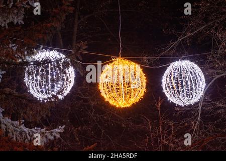 LED Christmas Light Balls hanging from the tree in the winter. Light spheres decoration. Stock Photo