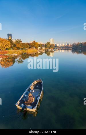 vienna,oxbow lake alte donau (old danube),dc tower 1,vienna international center vic (un building),izd tower,donaucity,boat with angler,autumn colors in 22. donaustadt,vienna,austria Stock Photo