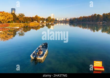 vienna,oxbow lake alte donau (old danube),dc tower 1,vienna international center vic (un building),izd tower,donaucity,boat with angler,autumn colors in 22. donaustadt,vienna,austria Stock Photo