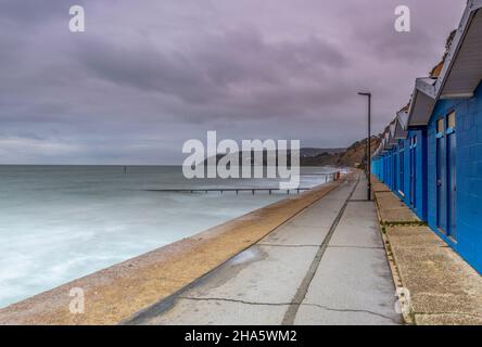 beach huts on isle of wight coastline at shanklin, blue painted beach huts in a row or terrace at shankling sea front on the isle of wight shoreline. Stock Photo