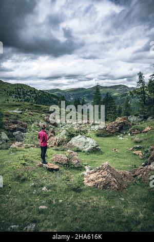 Woman stands on a rock and takes cell phone pictures of the red rocks at the red castle, Nockberge Biosphere Park, Carinthia, Austria, Europe. Stock Photo