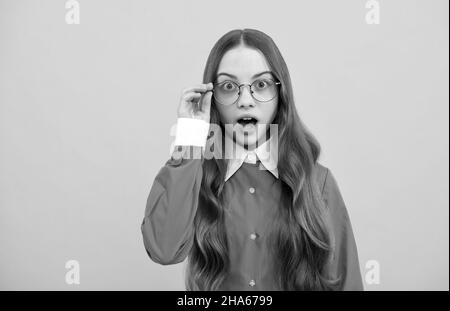 Surprised teenage girl fix eyeglasses yellow background, surprise Stock Photo