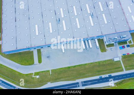 Aerial Shot of Industrial Warehouse Loading Dock where Many Truck with Semi Trailers Load Merchandise. Stock Photo