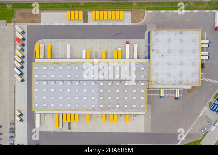 Aerial view of goods warehouse. Logistics delivery; center in industrial city zone from above. Aerial view of trucks loading at logistic center. View Stock Photo