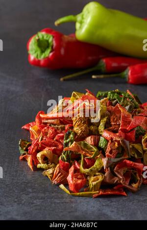 Assortment of Dried and Fresh Yellow, Green, Red and Orange Peppers on a Dark Grey Background. Dried Vegetables Concept Stock Photo