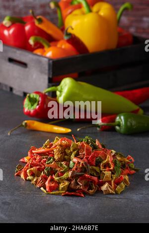 Assortment of Dried and Fresh Yellow, Green, Red and Orange Peppers on a Dark Grey Background. Dried Vegetables Concept Stock Photo