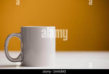 light gray cup of coffee on the table, with yellow background Stock Photo