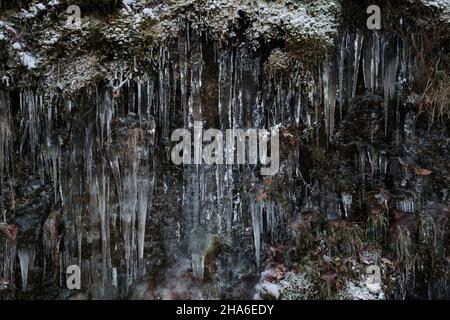 Icicle formations covering the mountain rock and mountain vegetation Stock Photo