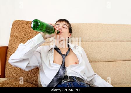Teenager drinks a Beer on the Sofa at the Home Stock Photo