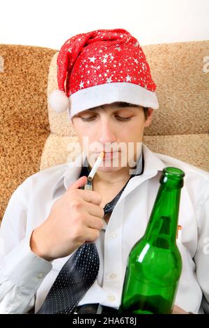 Teenager in Santa Hat with Bottle of the Beer smoking Cigarette Stock Photo