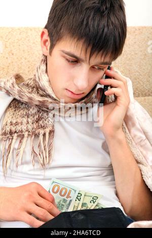Sick Teenager with Cellphone checking the Wallet on the Sofa at the Home Stock Photo