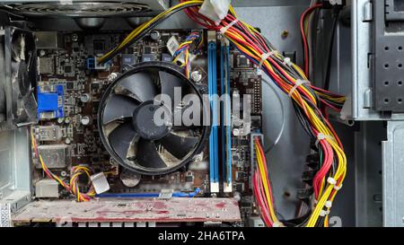 Disassembled dusty system unit. Man's hand scrolls a fan Stock Photo