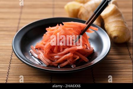 Red pickled ginger placed on a Japanese style background. Eating with chopsticks Stock Photo