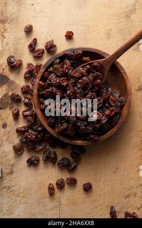 Raisins in a wooden bowl set against an old wooden background. View from directly above. Stock Photo