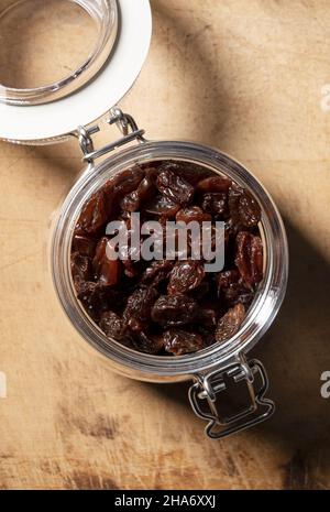 Raisins in a glass jar set against an old wooden background. View from directly above. Stock Photo
