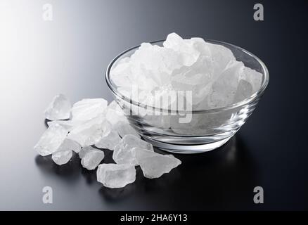 rock candy in a glass bowl set against a black background. Stock Photo