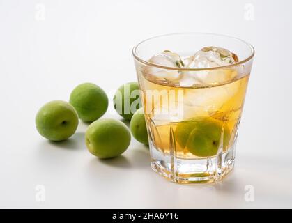 Japanese plum wine and unripe plums on a white background. Stock Photo