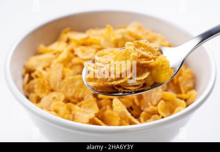 Cornflakes on a spoon. Cornflakes in a bowl in the background. Stock Photo