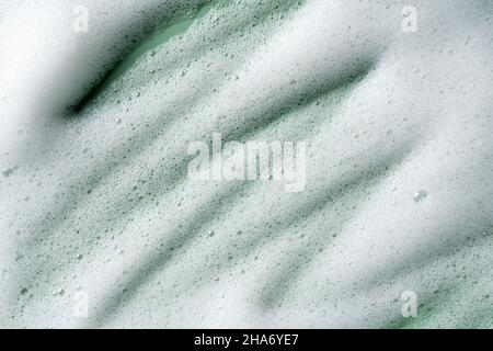 Bubbles texture background on green background. Soap, shampoo, mousse, shower gel foam. Stock Photo