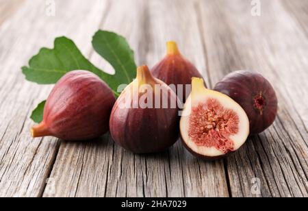 A lot of figs and cut figs on the old wooden background. Stock Photo