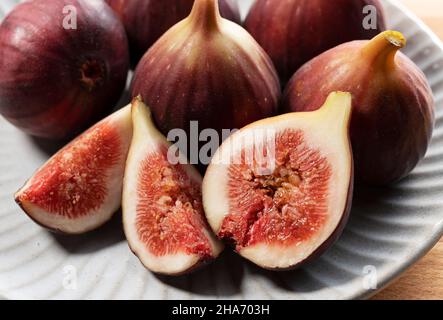 Figs and cut figs on a plate on the table. Image of figs. Close-up. Stock Photo