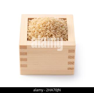 Brown rice in a wooden box set against a white background. Stock Photo