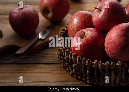 A lot of apples in a wooden basket placed in the wooden background. Stock Photo