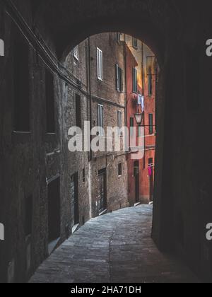 Alley in Siena, Via del Luparello, a Narrow and Dark Street Passage in the Old Town Stock Photo