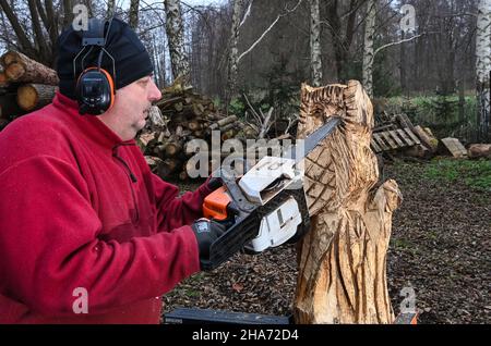 Diedersdorf, Germany. 08th Dec, 2021. Wood sculptor Torald Wendt creates works of art from wood with his chainsaw and thus unique for the garden, house and yard. With muscle power and a trained eye, an owl or even a torture stake in sizes between 30 centimetres and 20 metres are created from tree trunks. The sculptures are created according to the wishes of the customers. Logos and portraits can also be applied to the wood using a laser. Credit: Jens Kalaene/dpa-Zentralbild/ZB/dpa/Alamy Live News Stock Photo
