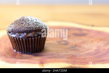 Chocolate Victoria Sponge Mini Cup Cake Filled with Cocoa Cream and Dusted with Sugar on Cherry Wooden Board with Space for Text Stock Photo