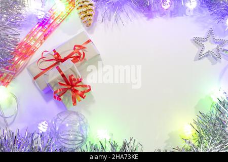 Background with New Year's festive garlands, luminous purple light, small gift boxes, tinsel and toys, with place for text. Stock Photo