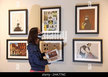 Aimie Rowe (arts development and outreach officer) chercking out works by Banksy, the URBAN art exhibition at Peterborough Museum and Art Gallery. The URBAN exhibition contains work from many contemporary artists including works by BANKSY, and opens from tomorrow until May 2022. URBAN art exhibition, Peterborough, Cambridgeshire, UK, on December 10, 2021 Stock Photo