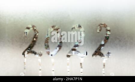 2022 new year concept. 2022 numbers written on the misted glass of the window. Abstract winter background. Selective focus. Banner. Stock Photo