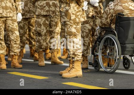 Romanian army veteran soldiers, of which one is injured and disabled, sitting in a wheelchair, prepare for the Romanian national day military parade. Stock Photo
